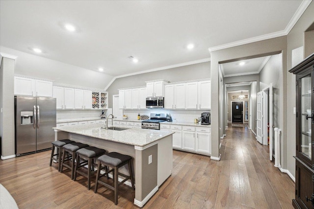 kitchen with white cabinets, a kitchen breakfast bar, wood finished floors, stainless steel appliances, and a sink