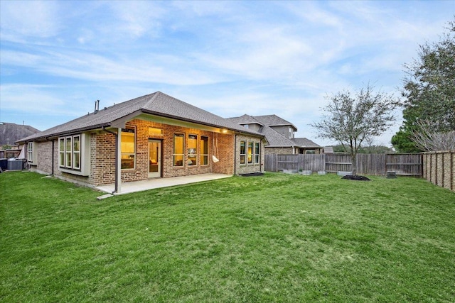 rear view of property with a lawn, a fenced backyard, a patio area, central AC, and brick siding