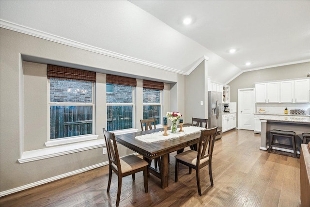 dining space featuring crown molding, recessed lighting, vaulted ceiling, wood finished floors, and baseboards