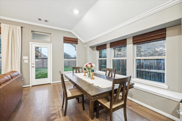 dining room with vaulted ceiling, crown molding, baseboards, and hardwood / wood-style flooring