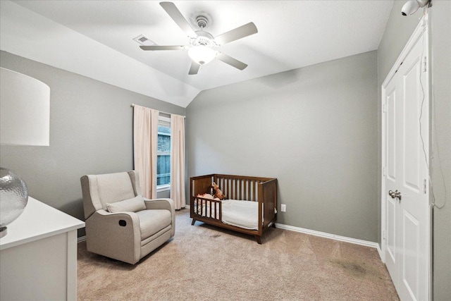 bedroom featuring lofted ceiling, light carpet, a ceiling fan, baseboards, and a nursery area