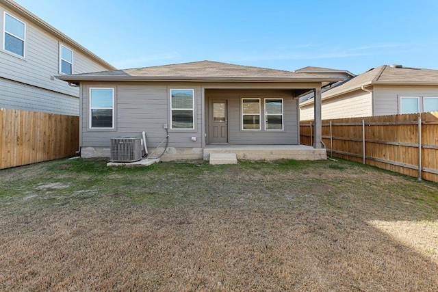 rear view of house featuring a fenced backyard, central AC unit, a patio, and a yard