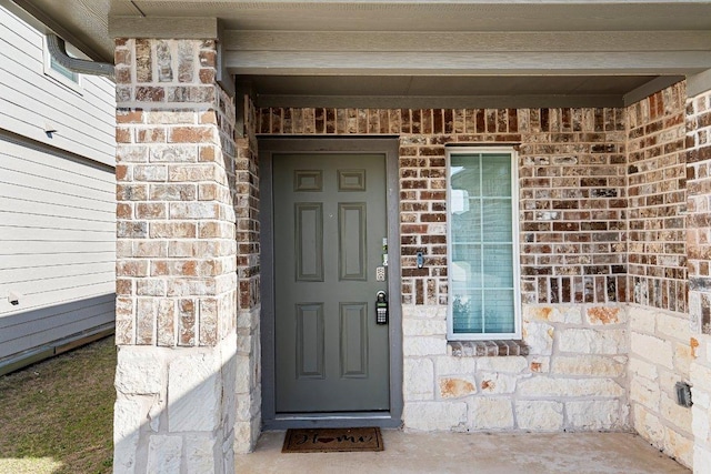 entrance to property featuring stone siding and brick siding