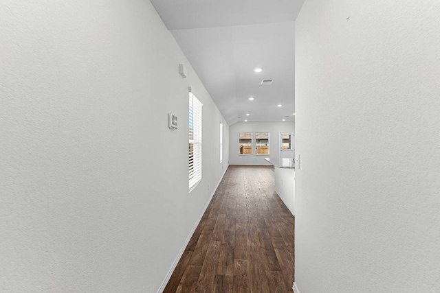 corridor featuring visible vents, baseboards, dark wood-type flooring, and a textured wall