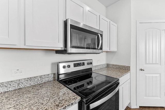 kitchen featuring appliances with stainless steel finishes, white cabinetry, and light stone countertops