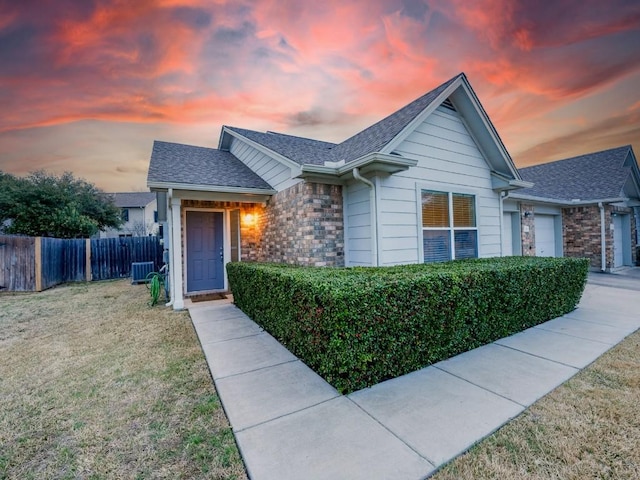 single story home featuring an attached garage, cooling unit, fence, a yard, and roof with shingles