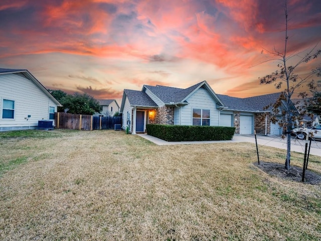 ranch-style house with a front lawn, an attached garage, fence, and central air condition unit