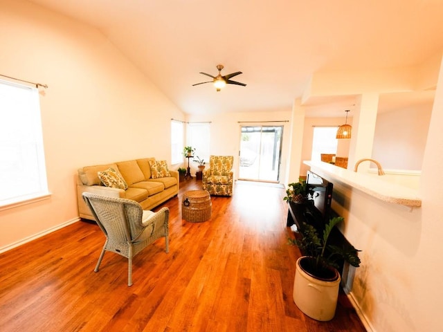 living area with ceiling fan, vaulted ceiling, baseboards, and wood finished floors