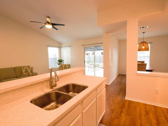 kitchen featuring light stone counters, pendant lighting, visible vents, dark wood-type flooring, and a sink