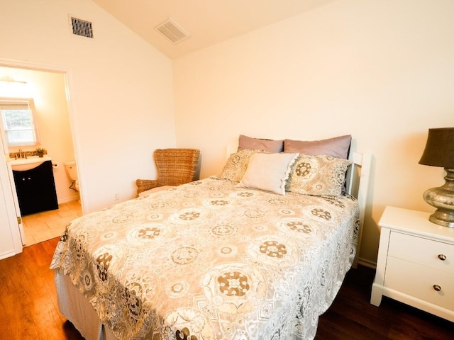 bedroom featuring vaulted ceiling, a sink, wood finished floors, and visible vents