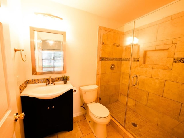 bathroom featuring toilet, a shower stall, vanity, tile patterned flooring, and baseboards