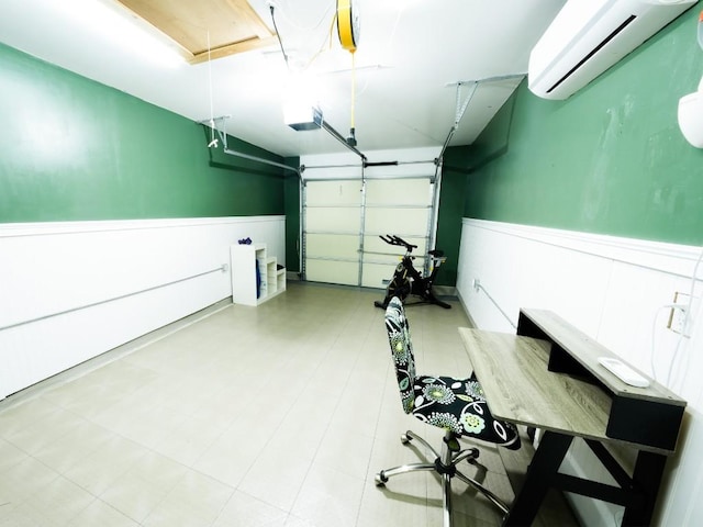 garage with a garage door opener, a wall mounted AC, and a wainscoted wall