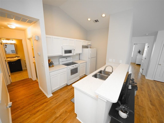 kitchen featuring visible vents, a sink, white cabinets, white appliances, and light wood-style flooring