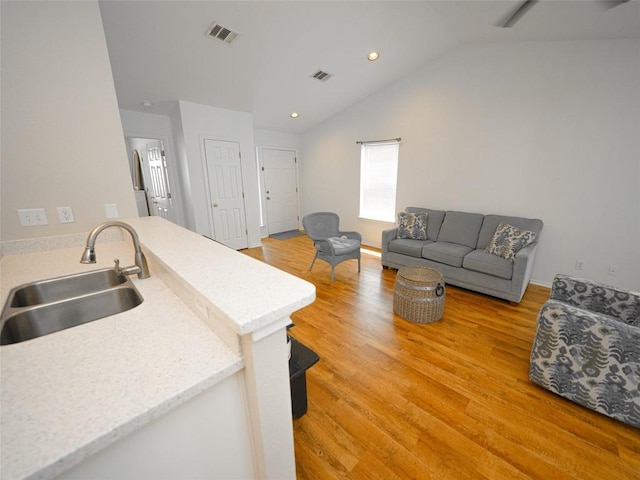 kitchen with visible vents, lofted ceiling, recessed lighting, a sink, and light wood finished floors