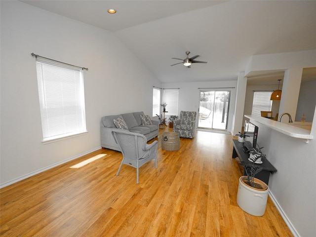 living room with light wood-type flooring, a ceiling fan, baseboards, and lofted ceiling