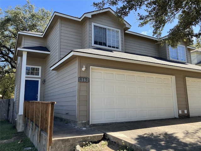 view of front of home featuring a garage, driveway, and fence