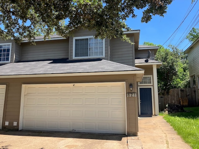 view of front of house with a garage, driveway, roof with shingles, and fence