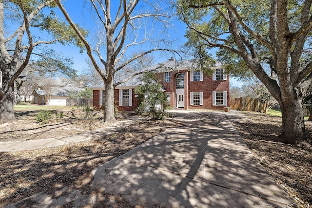 view of front of house with a chimney, fence, and brick siding