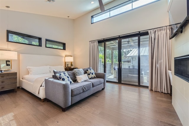 bedroom featuring a high ceiling, wood finished floors, visible vents, and access to exterior