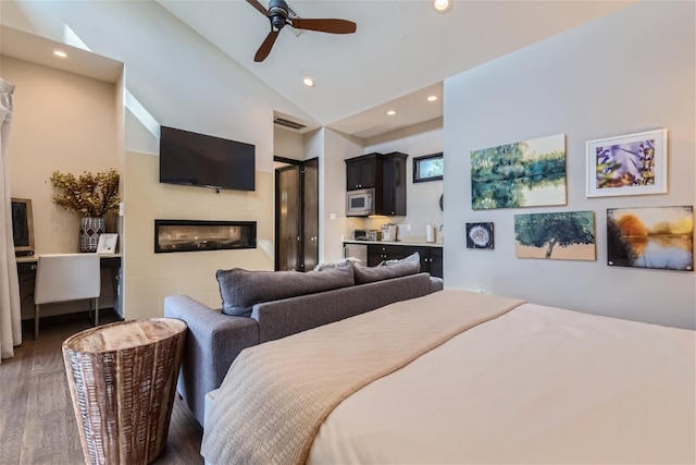 bedroom with a glass covered fireplace, ceiling fan, wood finished floors, vaulted ceiling, and recessed lighting