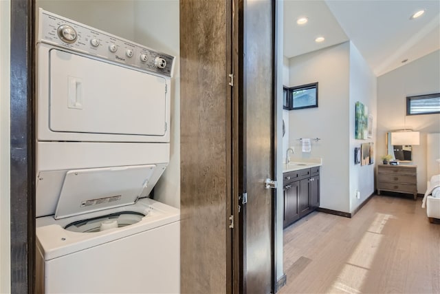 laundry area featuring recessed lighting, a sink, stacked washing maching and dryer, light wood-type flooring, and laundry area