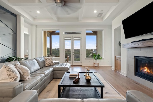 144 Sunnys Halo Ct, Austin, TX 78737 - living room featuring coffered ceiling, light wood-style floors, ceiling fan, french doors, and a tile fireplace