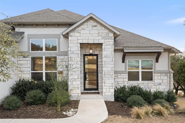 view of front of house featuring stone siding, a shingled roof, and stucco siding