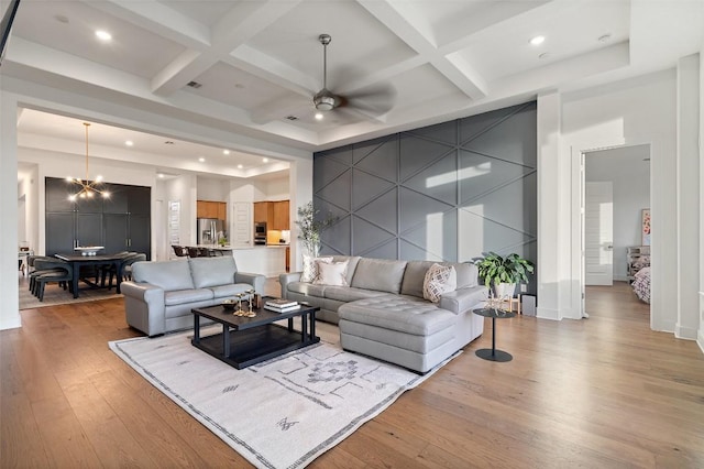 living room featuring light wood-style floors, an accent wall, beam ceiling, and coffered ceiling