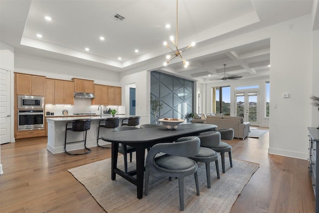 dining space with recessed lighting, a raised ceiling, visible vents, and wood finished floors