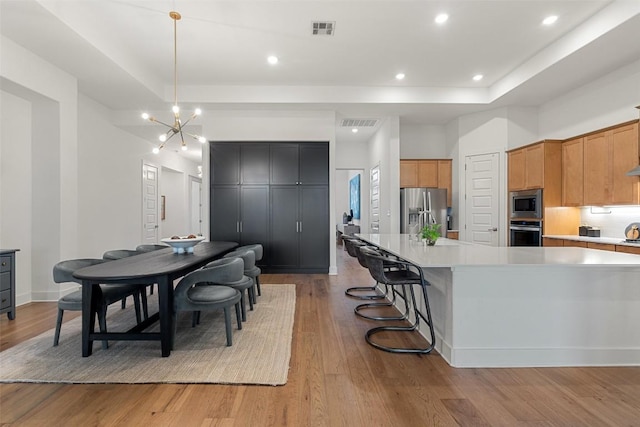 kitchen featuring appliances with stainless steel finishes, light wood-style flooring, a raised ceiling, and visible vents