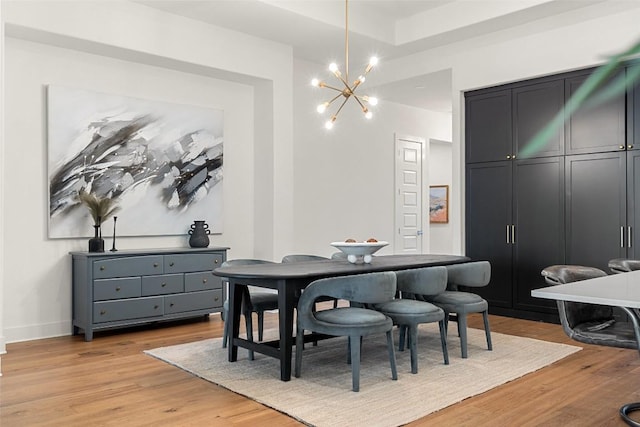 dining room with a notable chandelier, light wood-style flooring, and baseboards