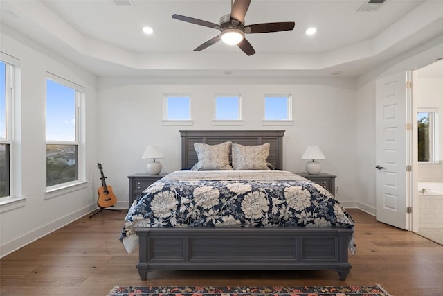 bedroom with recessed lighting, a raised ceiling, baseboards, and wood finished floors