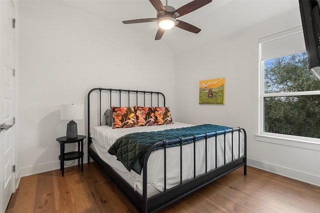 bedroom featuring lofted ceiling, wood finished floors, a ceiling fan, and baseboards