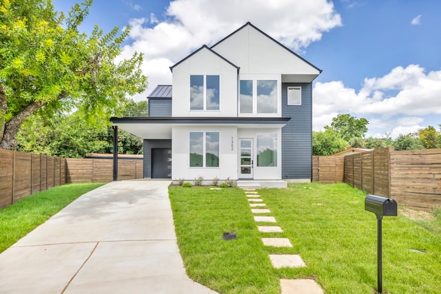 modern home with a front yard, a standing seam roof, metal roof, a fenced backyard, and driveway