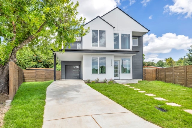 modern home with concrete driveway, a front lawn, and fence private yard