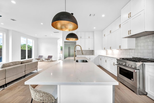 kitchen featuring a sink, visible vents, open floor plan, light wood-type flooring, and high end appliances