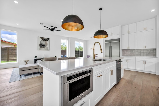 kitchen with oven, a sink, light countertops, backsplash, and stainless steel built in refrigerator