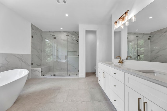 bathroom featuring toilet, double vanity, a marble finish shower, and a sink