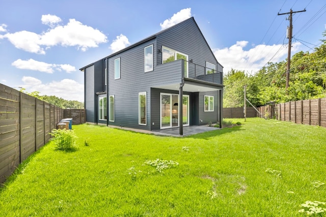 rear view of property featuring a yard, a patio area, a fenced backyard, and a balcony