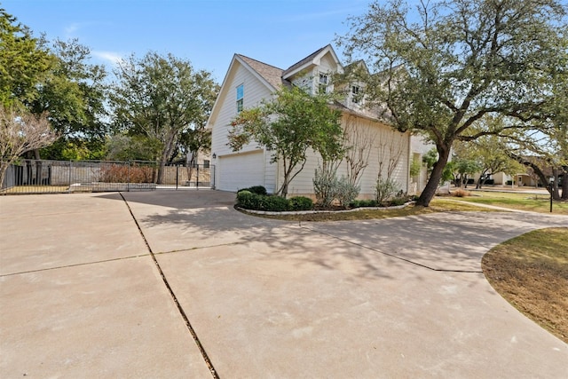 view of side of property featuring a garage, driveway, and fence