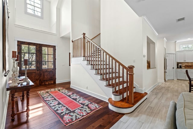 foyer featuring baseboards, crown molding, visible vents, and wood finished floors