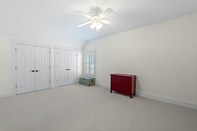 bedroom featuring lofted ceiling, ceiling fan, carpet flooring, baseboards, and two closets