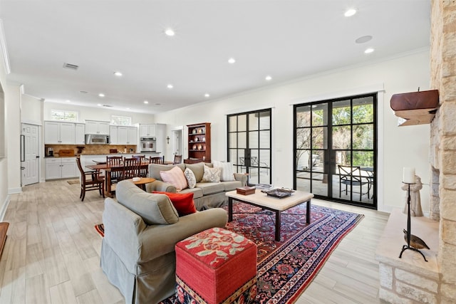 living area with recessed lighting, visible vents, crown molding, and light wood-style flooring