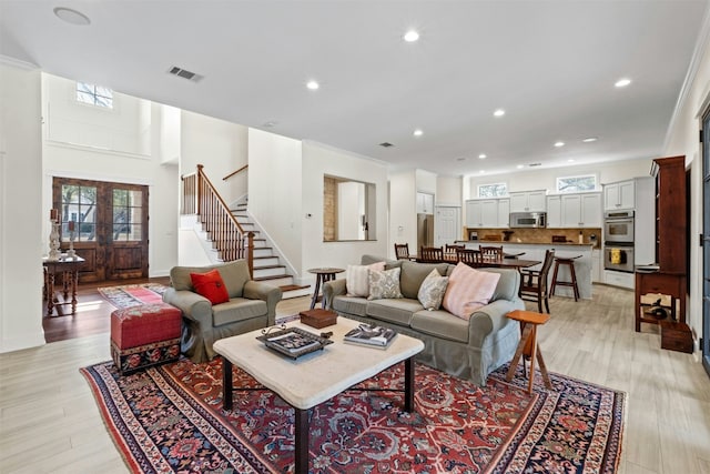 living room featuring recessed lighting, a healthy amount of sunlight, stairway, and light wood finished floors