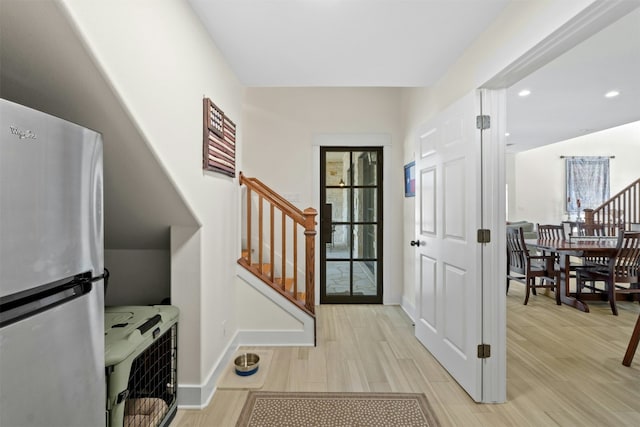 foyer featuring heating unit, baseboards, stairway, and light wood finished floors