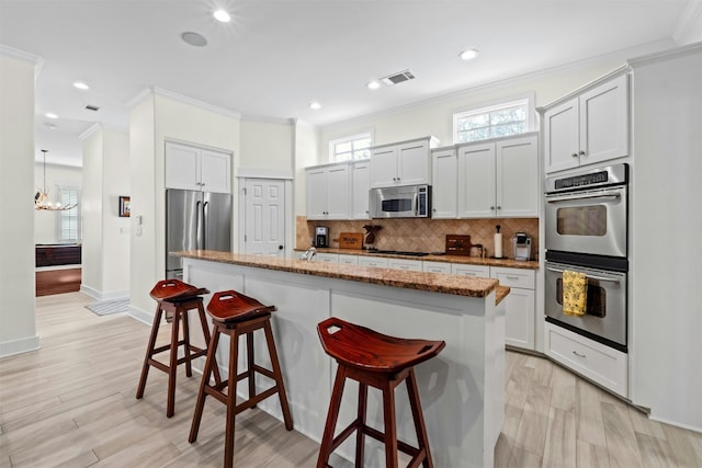 625 Robin Dale Ct, Lakeway, TX 78734 - kitchen featuring appliances with stainless steel finishes, crown molding, a kitchen bar, tasteful backsplash, and stone countertops