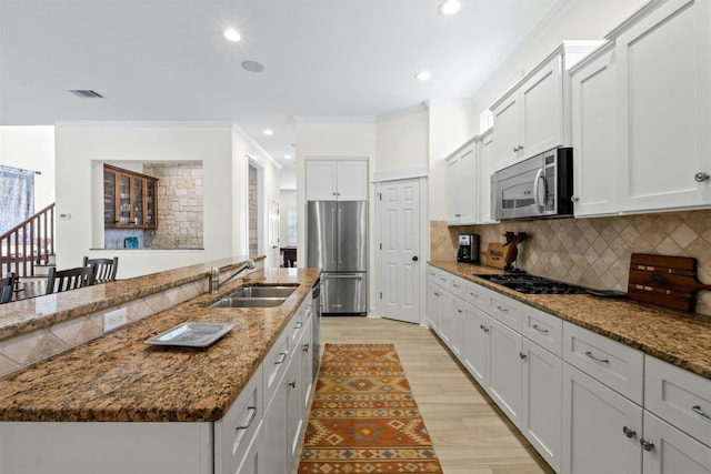 kitchen featuring stainless steel appliances, visible vents, backsplash, ornamental molding, and a sink