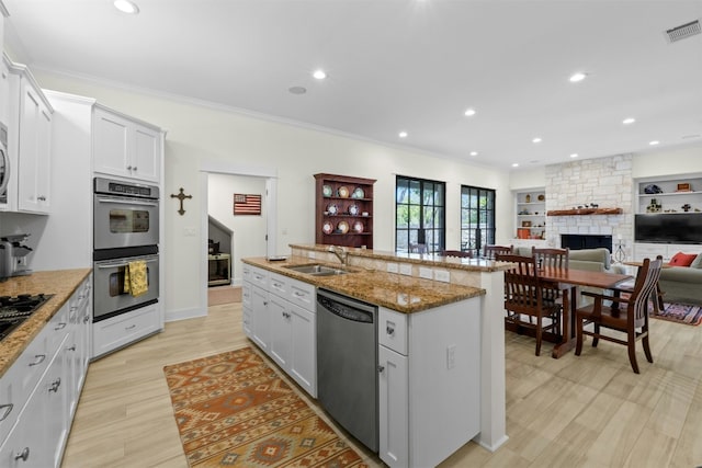 625 Robin Dale Ct, Lakeway, TX 78734 - kitchen featuring stainless steel appliances, a sink, a stone fireplace, a center island with sink, and crown molding