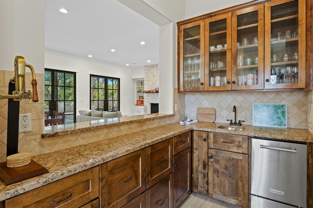 interior space featuring tasteful backsplash, glass insert cabinets, a sink, light stone countertops, and dishwasher