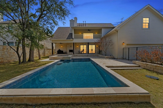 rear view of property with a balcony, ceiling fan, a chimney, a fenced backyard, and a patio area